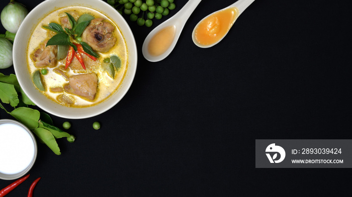 Top view of chicken green curry and ingredients on black desk background, Thai cuisine concept