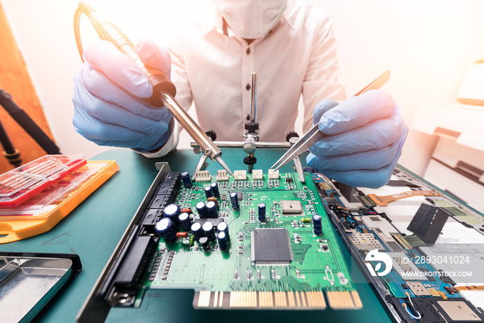 The technician repairing the computer mainboard by soldering in the lab. The concept of computer har