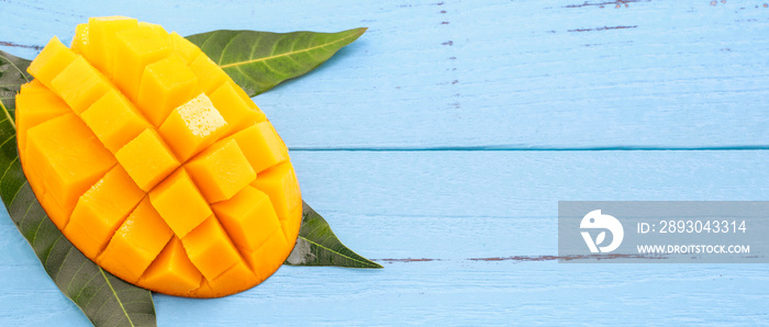 Fresh chopped mango with green leaves on bright blue color timber background. Above Top view, flat l