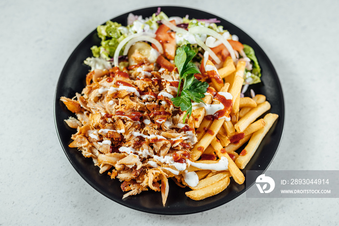 Doner Kebab on plate with vegetables fries and souce, grilled meat on plate