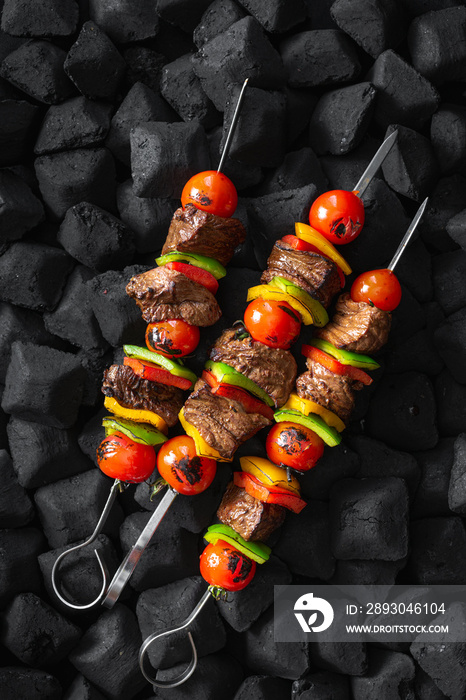 Beef skewers being grilled on a embers top view