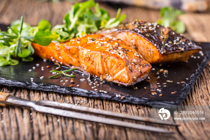 Salmon fillets. Grilled salmon, sesame seeds herb decorationon on vintage pan or black slate board. 