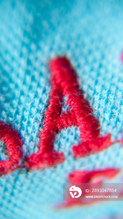 Letra A bordada con hilo rojo en tejido de algodón azul