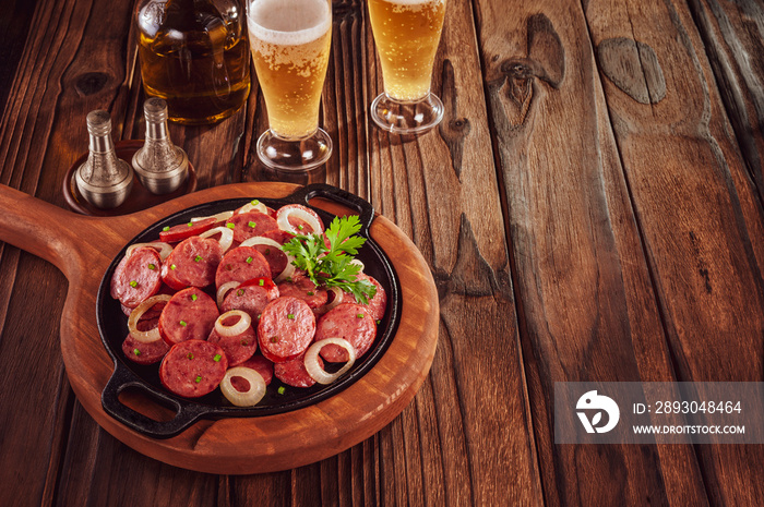 Sliced smoked fried calabrese sausage with onion and beer - Brazilian appetizer with space copy