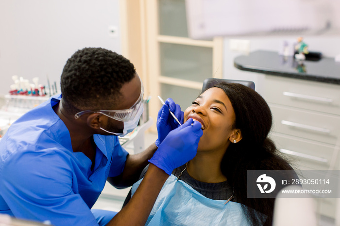 非洲男牙医在牙科诊所用工具检查病人。