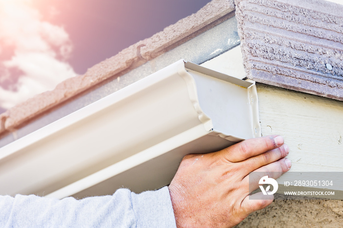 Worker Attaching Aluminum Rain Gutter to Fascia of House