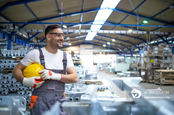 Portrait of industrial engineer. Smiling factory worker with hard hat standing in factory production