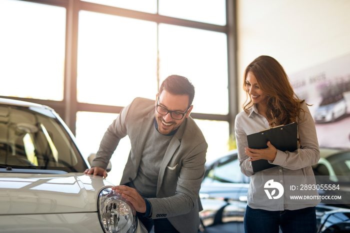 Happy car buyer and salesperson at vehicle dealership showroom. Car purchase.