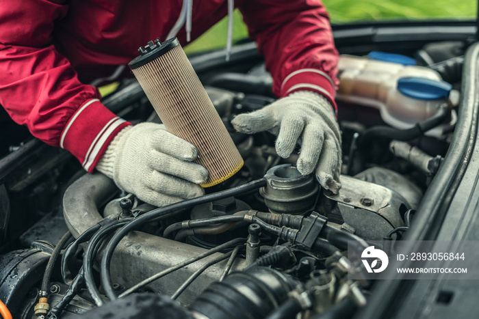 The auto mechanic replaces the cars oil filter.