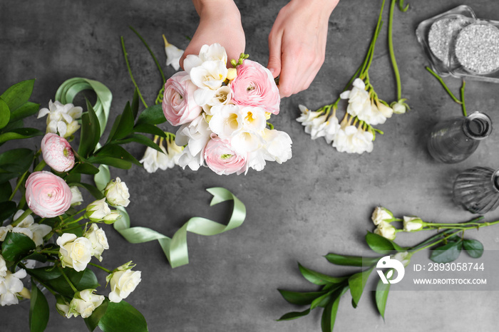 女花艺师用灰色背景的小苍兰花制作美丽的花束