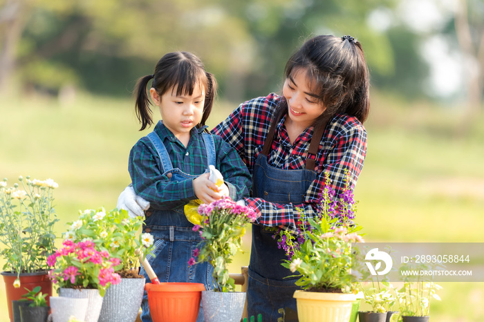 家庭小女孩帮助母亲在花园里种花。年轻人母女园丁