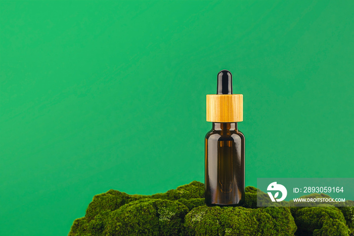 Amber glass dropper bottle with bamboo lid on green moss. Skincare products ,natural cosmetic. Beaut