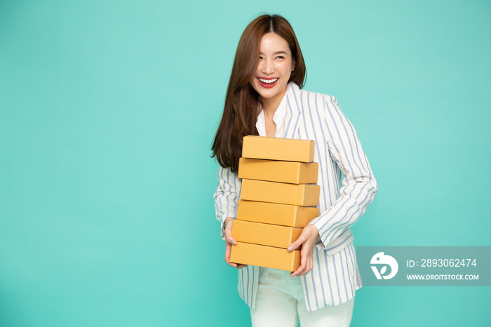 Happy Asian woman smiling and holding package parcel box isolated on light green background, Deliver