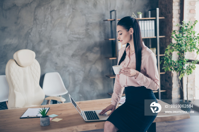 Photo of beautiful attractive business woman sitting on desktop enjoying cup of warm tea looking int