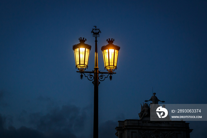 Old fashioned street lamp at night. Magic lamp with a warm yellow light in the city twilight