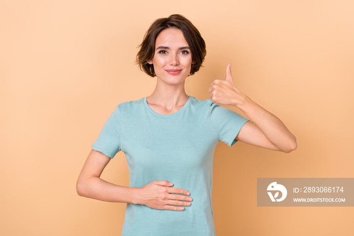 Photo of young woman armn on stomach show thumb-up ideal select approve isolated over beige color ba