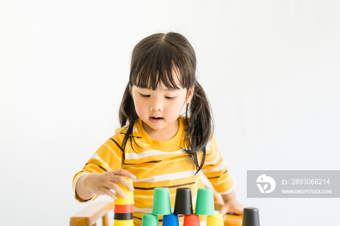 Little asian toddler girl playing stacking cups learning materials in a montessori methodology schoo