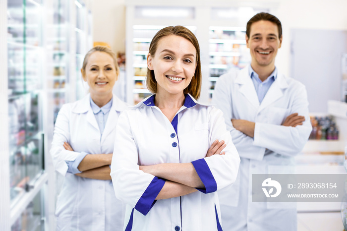 Cheerful three pharmacists waiting for customers in a drugstore