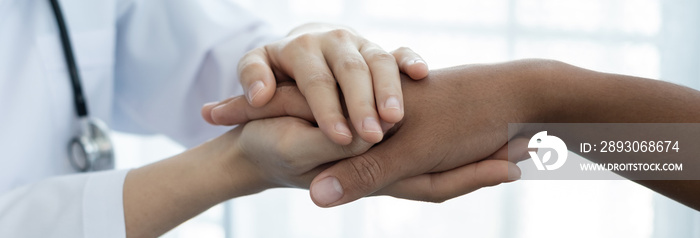 女医生用一只友好的手握住病人的手，给他们信心和关怀。