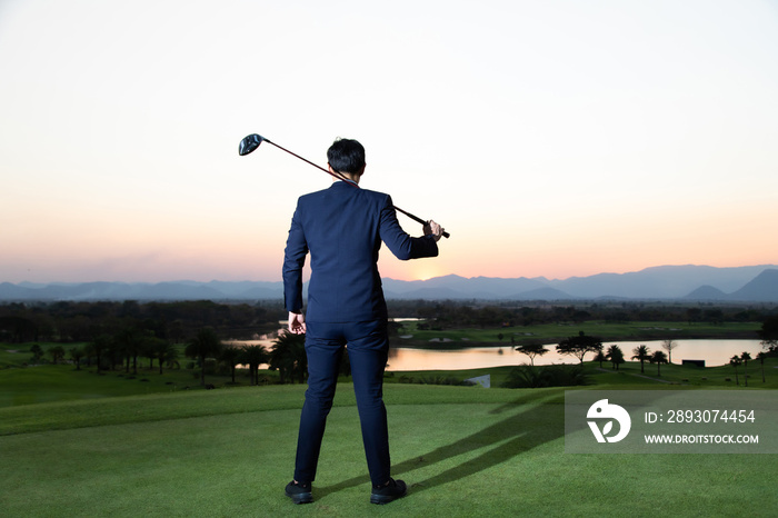 年轻的亚洲首席执行官商人穿着西装在高尔夫球场打高尔夫的背影。
