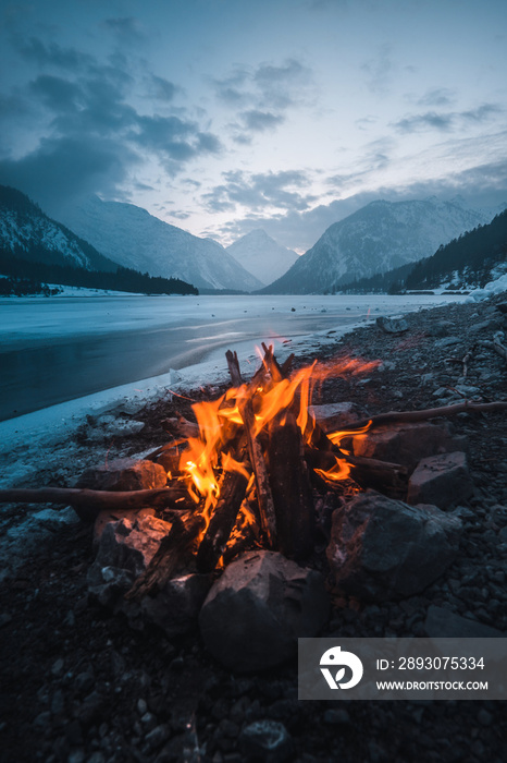 夜晚在结冰的湖面上的冬季篝火，日落时的壮丽景色