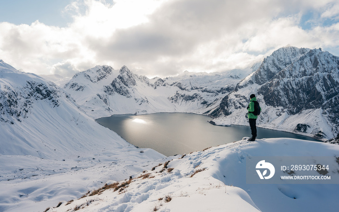 Hiking on snowshoes on a trail. Man trekking in snow covered mountain landscape overlooking Luenerse