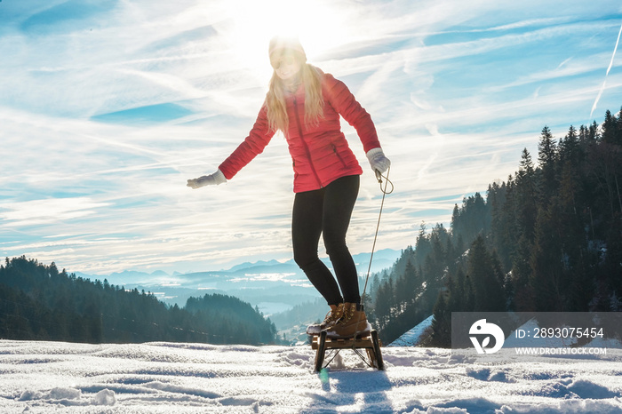 年轻女子在雪山上驾驶老式雪橇超速行驶-快乐女孩穿着白色的我们玩得很开心