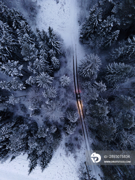 Aerial view of road and car in winter night forest. Forest work Establishing shots of a car in the w
