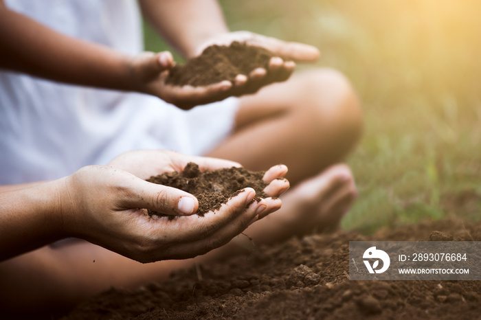 Child and parent holding soil and preparing soil for plant the tree together