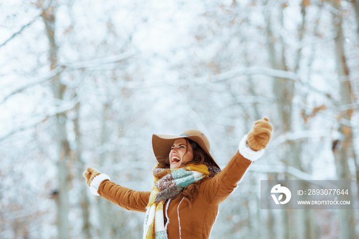 happy elegant woman rejoicing outside in city park in winter