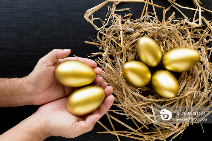 巢中满是金蛋，黑色背景下拿着金蛋的男人。财务成功