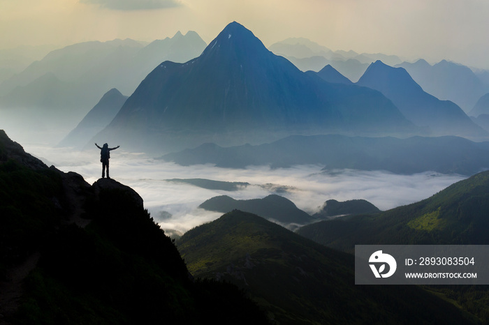 Wide mountain panorama. Small silhouette of tourist with backpack on rocky mountain slope with raise