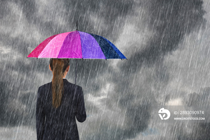 business woman holding multicolored umbrella under sky with falling rain