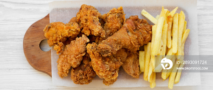 Tasty fastfood: fried chicken drumsticks, spicy wings, French fries and chicken strips over white wo