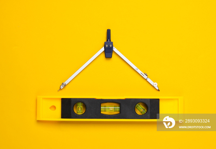 Engineering construction supplies on yellow background. Construction level and compass. Top view