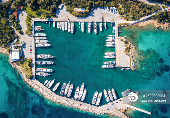 Top down Luftaufnahme einer Bootsmarina mit Segelbooten und Motoryachten über türkisem Meer