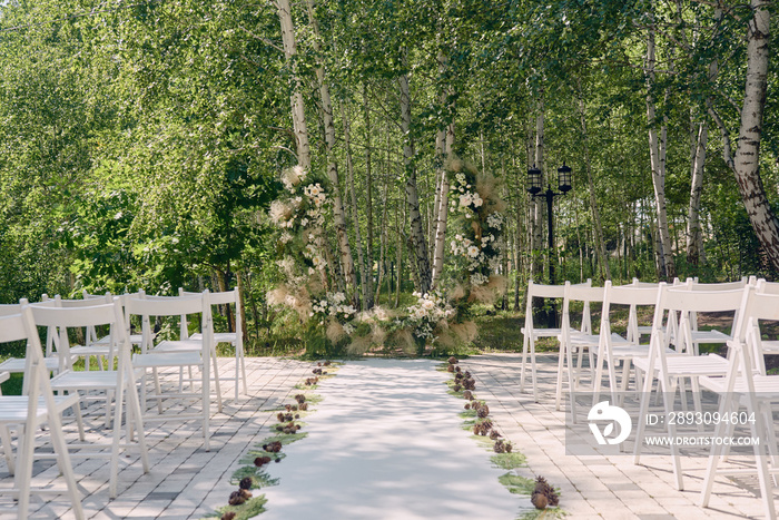 花园里举行婚礼的地方，复制空间。婚礼拱门上装饰着鲜花和白柴