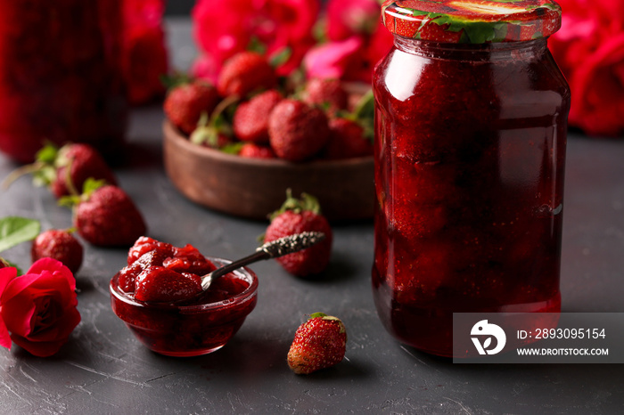 Strawberry jam in a can and fresh strawberries on a dark background, summer harvest