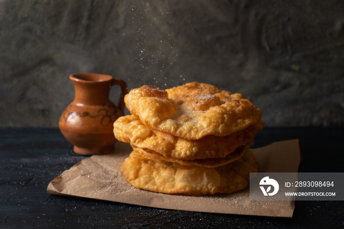 mexican fritter dusted with sugar also called  buñuelos  on dark background