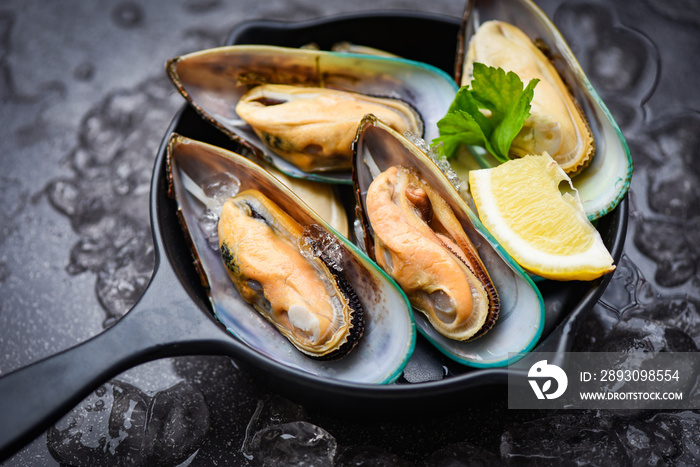 Fresh mussels on black bowl and ice with lemon and lettuce for cooked food / Seafood shellfish steam