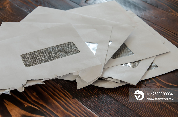 Stack of opened envelopes laying on wooden table. Pile of letters with window.