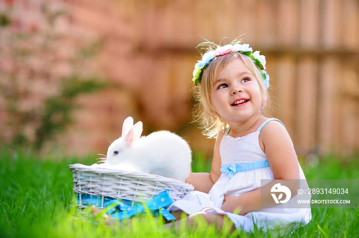 可爱的小女孩带着一只兔子在绿色的草地上过复活节