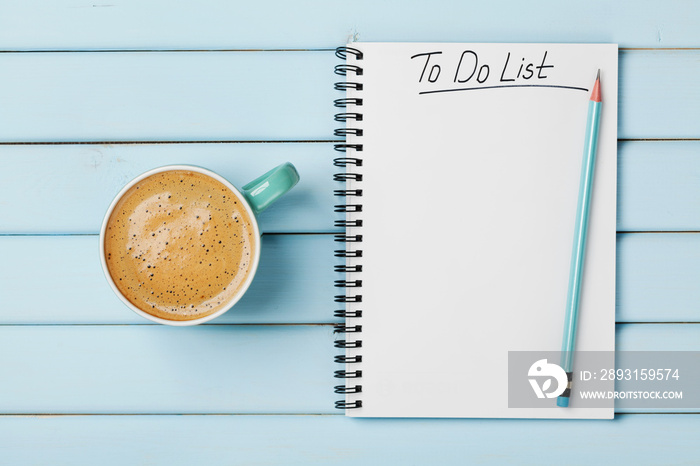 Coffee cup and notebook with to do list on blue rustic desk from above, planning and design concept