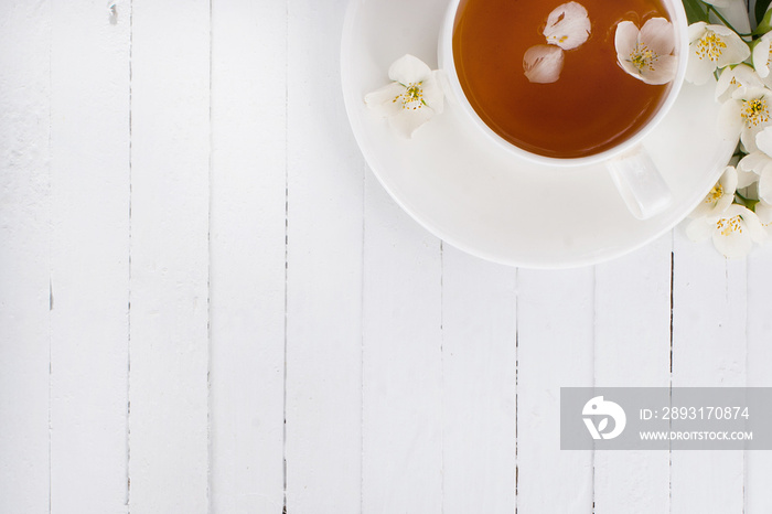 A cup of green tea with jasmine on a white surface