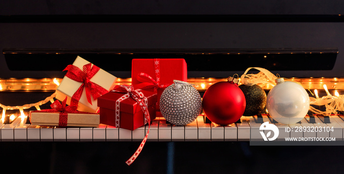 钢琴键盘上的圣诞球和礼品盒，前视图