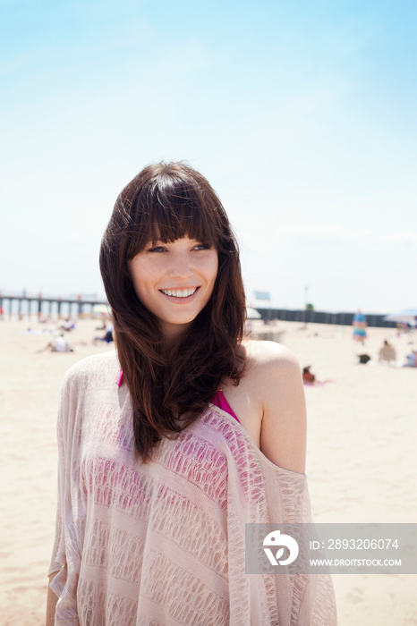 Smiling woman standing at beach against clear sky during summer