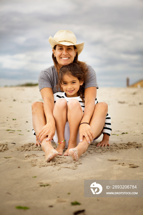 Mather and daughter (6-7) sitting on beach