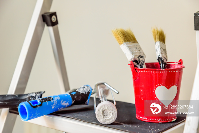 Day view Red Bucket with Heart on it and two paint brushes inside. Valentines decorating concept