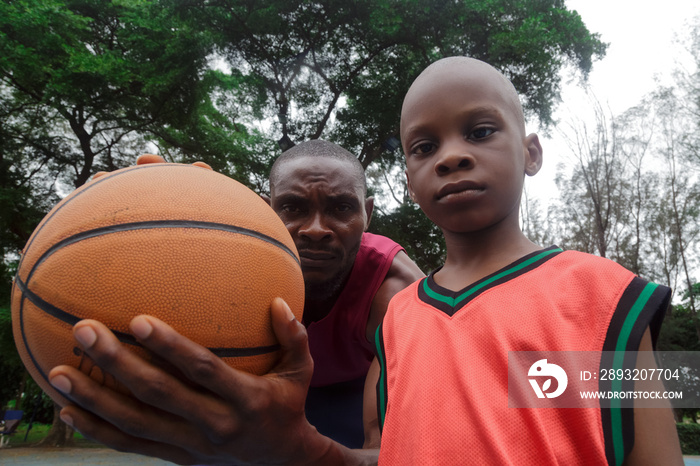 Boy standing beside father holding a basketball