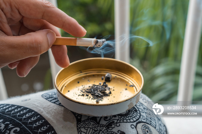 Lighted cigarette in a golden ashtray